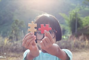 Little child holding piece of blank jigsaw puzzle